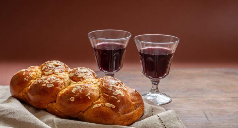 Challah bread with two glasses of red wine on wooden table