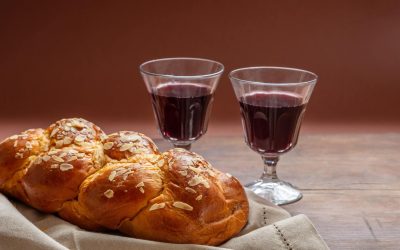 Challah bread with two glasses of red wine on wooden table