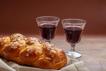 Challah bread with two glasses of red wine on wooden table